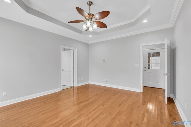 unfurnished room featuring crown molding, a tray ceiling, light hardwood / wood-style floors, and ceiling fan