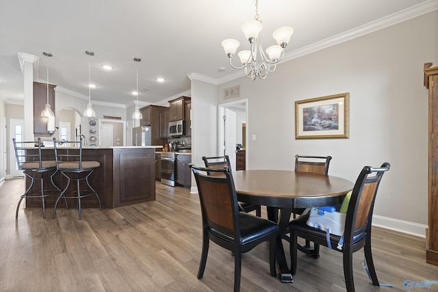 dining area featuring crown molding, an inviting chandelier, and light hardwood / wood-style floors