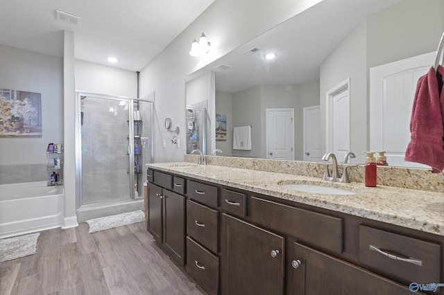 bathroom featuring hardwood / wood-style flooring, vanity, and plus walk in shower