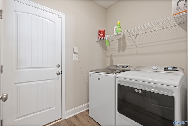 clothes washing area with separate washer and dryer and hardwood / wood-style floors