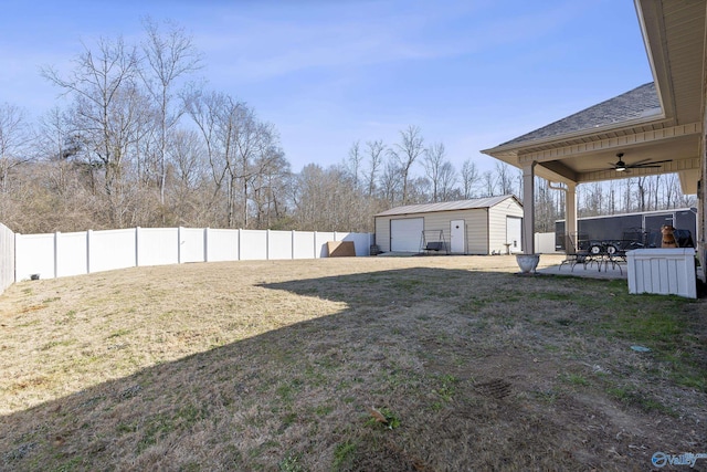 view of yard with a garage, an outdoor structure, a patio, and ceiling fan