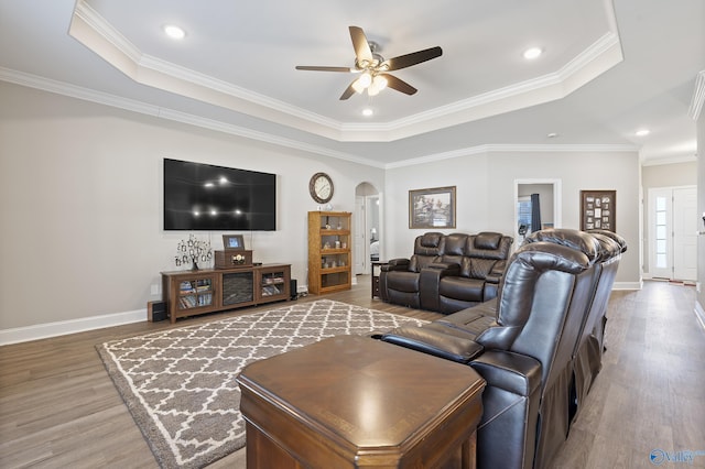 living room featuring a raised ceiling, ornamental molding, hardwood / wood-style floors, and ceiling fan