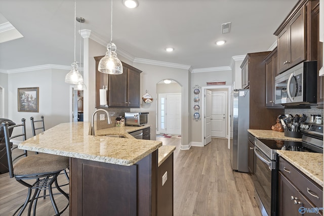 kitchen featuring appliances with stainless steel finishes, a breakfast bar, decorative light fixtures, sink, and kitchen peninsula