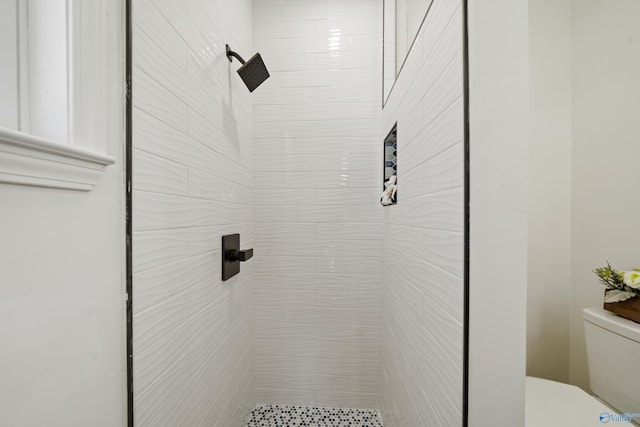 bathroom featuring tiled shower and toilet