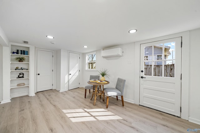 interior space featuring light wood-style flooring, baseboards, and a wall mounted AC