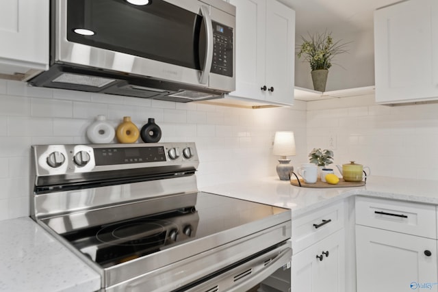 kitchen with light stone countertops, white cabinetry, appliances with stainless steel finishes, and decorative backsplash