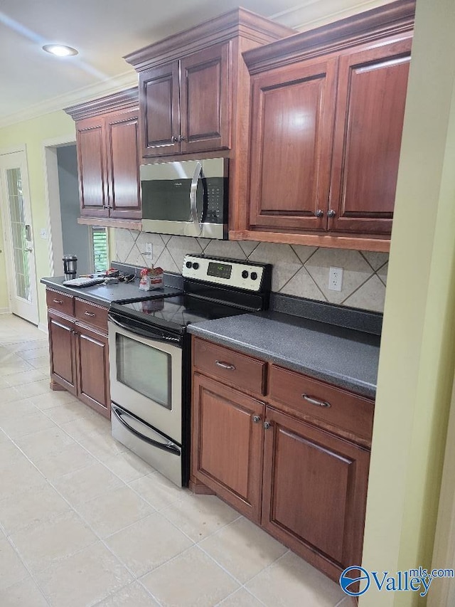 kitchen featuring crown molding, tasteful backsplash, dark countertops, appliances with stainless steel finishes, and light tile patterned flooring