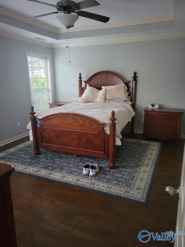 bedroom featuring a tray ceiling, ornamental molding, ceiling fan, wood finished floors, and baseboards