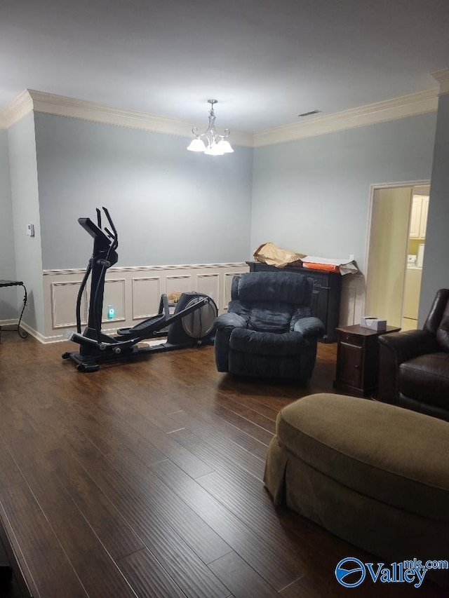 exercise room featuring an inviting chandelier, a decorative wall, crown molding, and wood finished floors