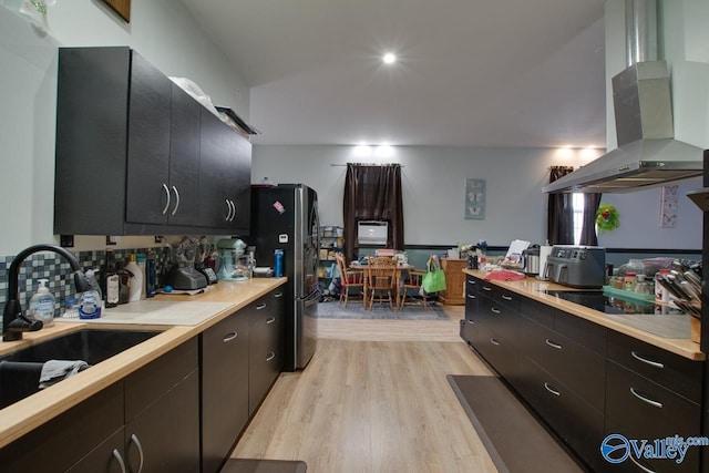 kitchen featuring island range hood, sink, stainless steel fridge, black electric stovetop, and light wood-type flooring