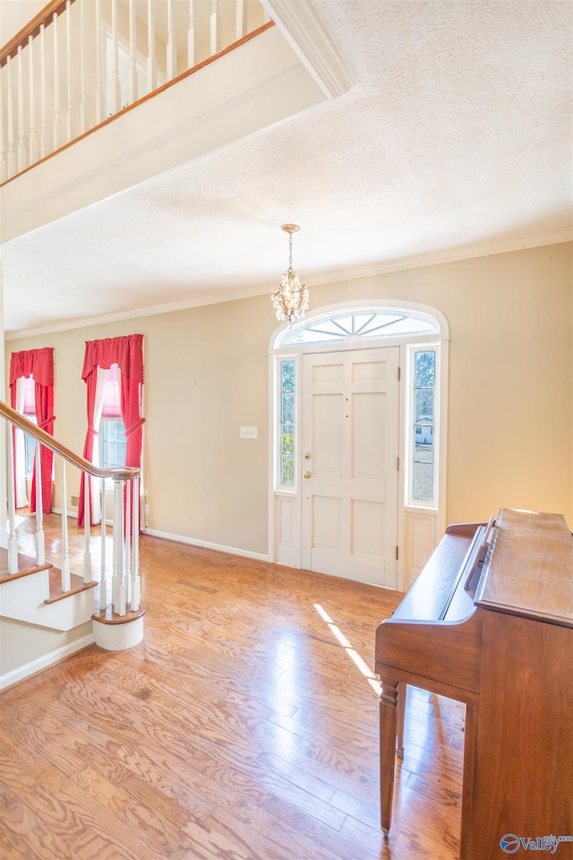 foyer entrance featuring a textured ceiling, hardwood / wood-style flooring, and an inviting chandelier