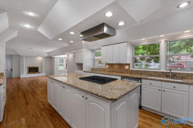 kitchen featuring sink, white cabinetry, island exhaust hood, black gas cooktop, and a kitchen island