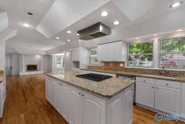 kitchen featuring sink, black gas cooktop, ventilation hood, white cabinets, and a kitchen island