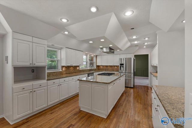 kitchen featuring white cabinetry, appliances with stainless steel finishes, a center island, and dark stone countertops