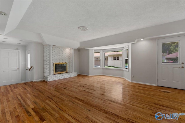 unfurnished living room featuring a fireplace, hardwood / wood-style floors, and a textured ceiling