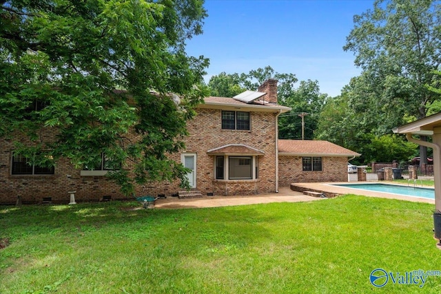 rear view of property with a patio, a yard, and solar panels