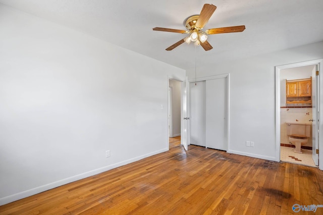 unfurnished bedroom featuring a closet, wood-type flooring, connected bathroom, and baseboards