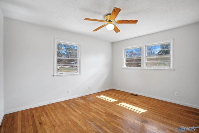 spare room with a ceiling fan, a textured ceiling, baseboards, and hardwood / wood-style flooring