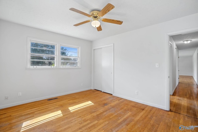 unfurnished bedroom featuring baseboards, visible vents, a ceiling fan, light wood-style floors, and a closet