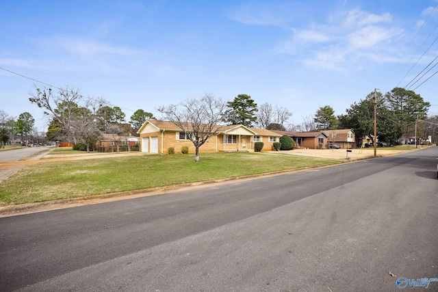 view of front of house with brick siding, an attached garage, a front yard, a residential view, and driveway