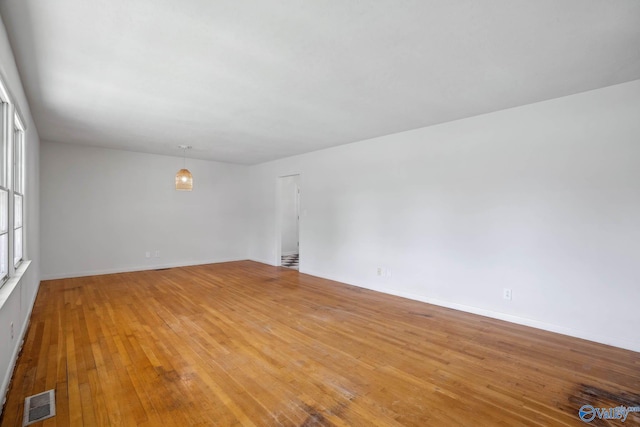 spare room featuring light wood finished floors, baseboards, and visible vents