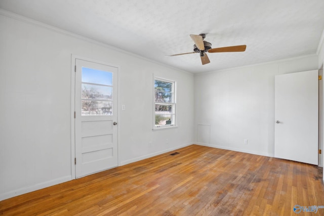 unfurnished room featuring baseboards, visible vents, a ceiling fan, light wood-style flooring, and ornamental molding