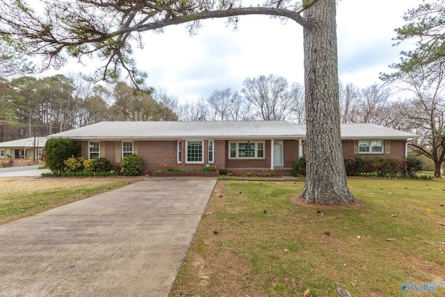 ranch-style house featuring metal roof, brick siding, concrete driveway, and a front lawn