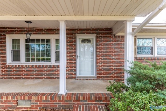 property entrance featuring brick siding and a porch