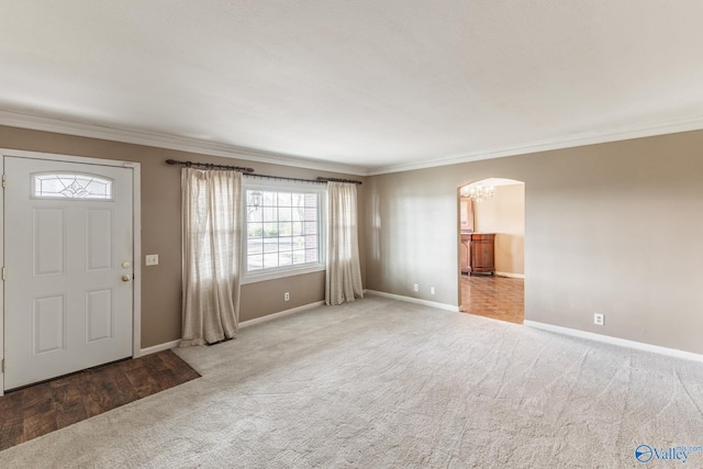 carpeted entryway with baseboards, arched walkways, an inviting chandelier, and crown molding