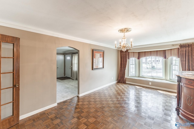 unfurnished room with baseboards, arched walkways, an inviting chandelier, and crown molding