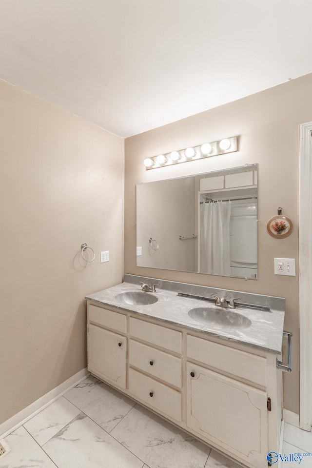 full bathroom featuring a sink, baseboards, marble finish floor, and double vanity