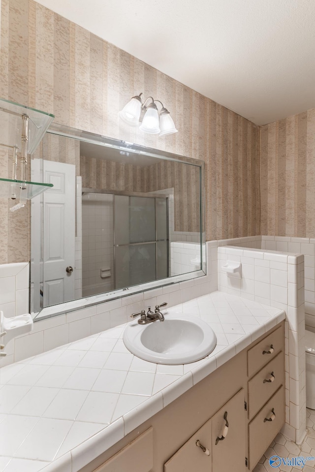 full bathroom featuring tile patterned flooring, wallpapered walls, toilet, vanity, and a shower