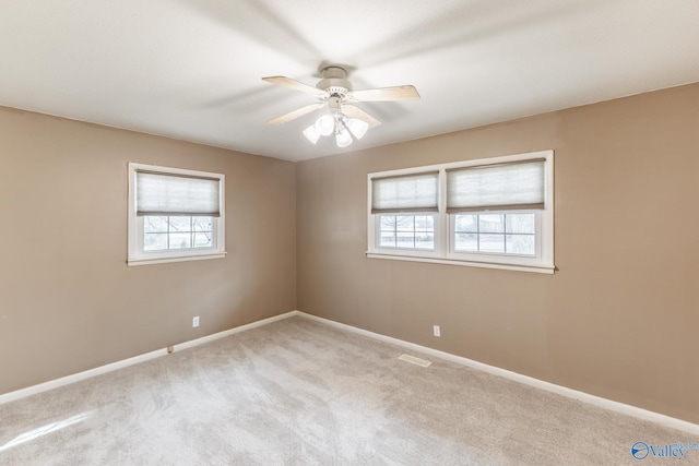 empty room with carpet flooring, ceiling fan, visible vents, and baseboards