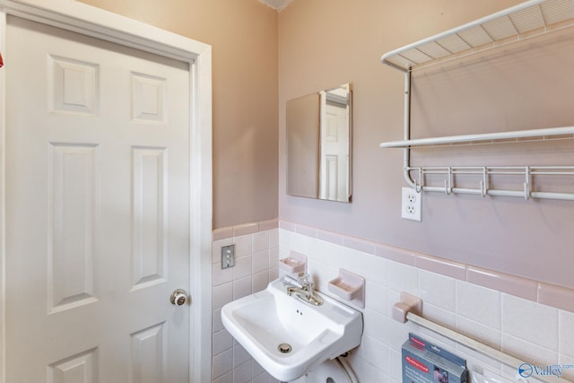 bathroom featuring a sink, a wainscoted wall, and tile walls