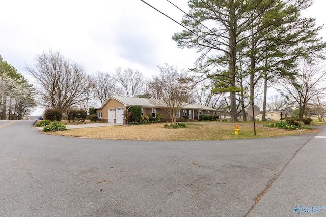 ranch-style home with a front yard, an attached garage, and driveway