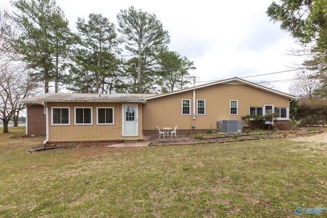 rear view of house featuring a yard, a patio, brick siding, and cooling unit