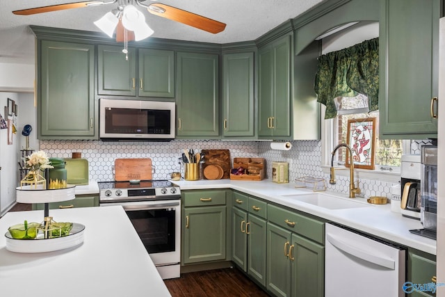 kitchen with green cabinets, appliances with stainless steel finishes, and a sink