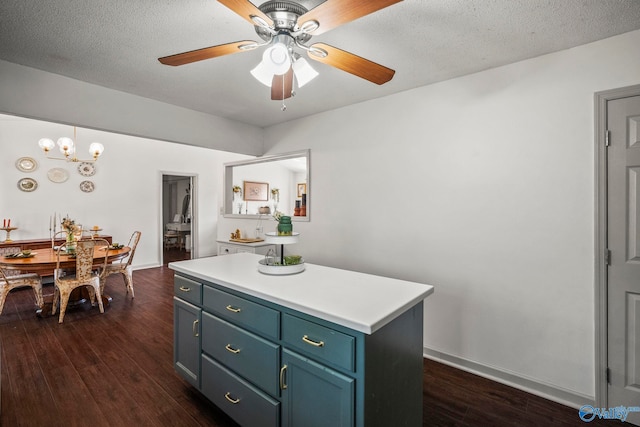 kitchen featuring a kitchen island, dark wood finished floors, light countertops, ceiling fan with notable chandelier, and a textured ceiling