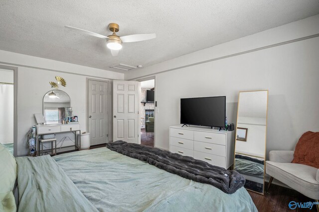 bedroom featuring a ceiling fan, attic access, wood finished floors, and a textured ceiling