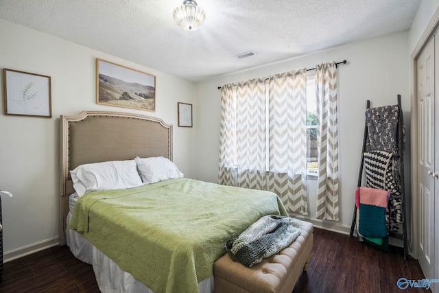 bedroom featuring wood finished floors, baseboards, visible vents, a closet, and a textured ceiling