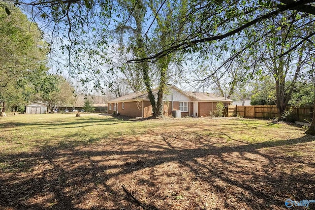 view of yard with an outbuilding, a storage shed, and fence