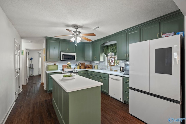 kitchen with white appliances, visible vents, a sink, light countertops, and green cabinets