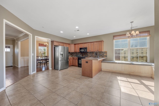 kitchen with tasteful backsplash, a notable chandelier, black appliances, decorative light fixtures, and kitchen peninsula