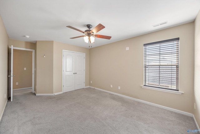 unfurnished bedroom with light carpet, ceiling fan, and a closet