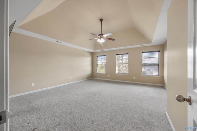 carpeted empty room featuring ceiling fan, a tray ceiling, and a healthy amount of sunlight