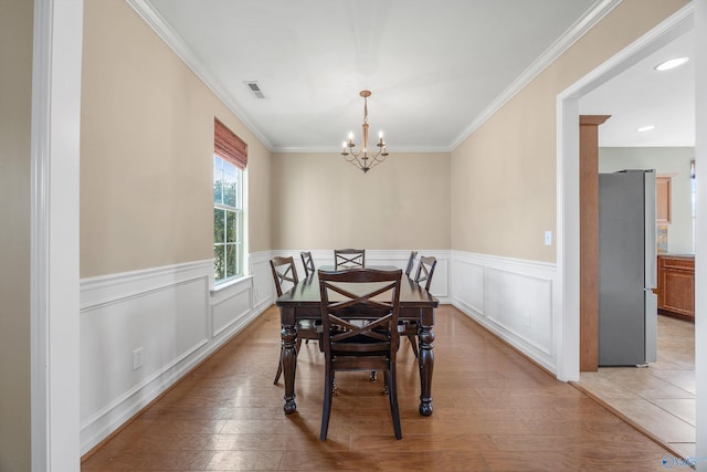 dining room with ornamental molding, a chandelier, and light hardwood / wood-style floors