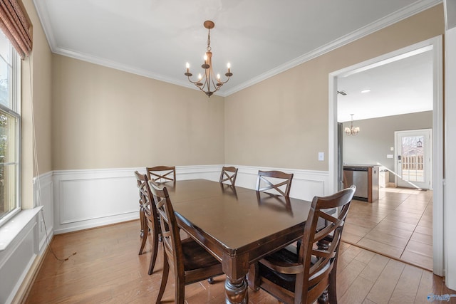 dining area featuring crown molding, light hardwood / wood-style flooring, and a chandelier