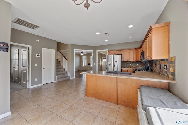 kitchen featuring light tile patterned floors, stainless steel fridge, kitchen peninsula, ceiling fan, and backsplash