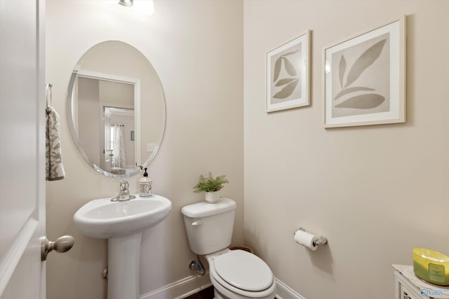 bathroom with toilet, baseboards, and a sink