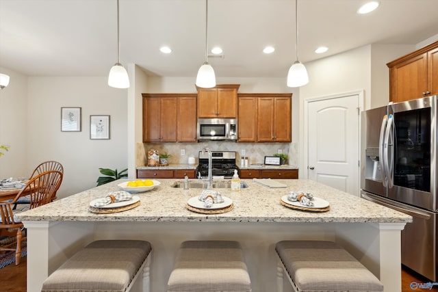 kitchen with decorative backsplash, brown cabinets, appliances with stainless steel finishes, and a breakfast bar area